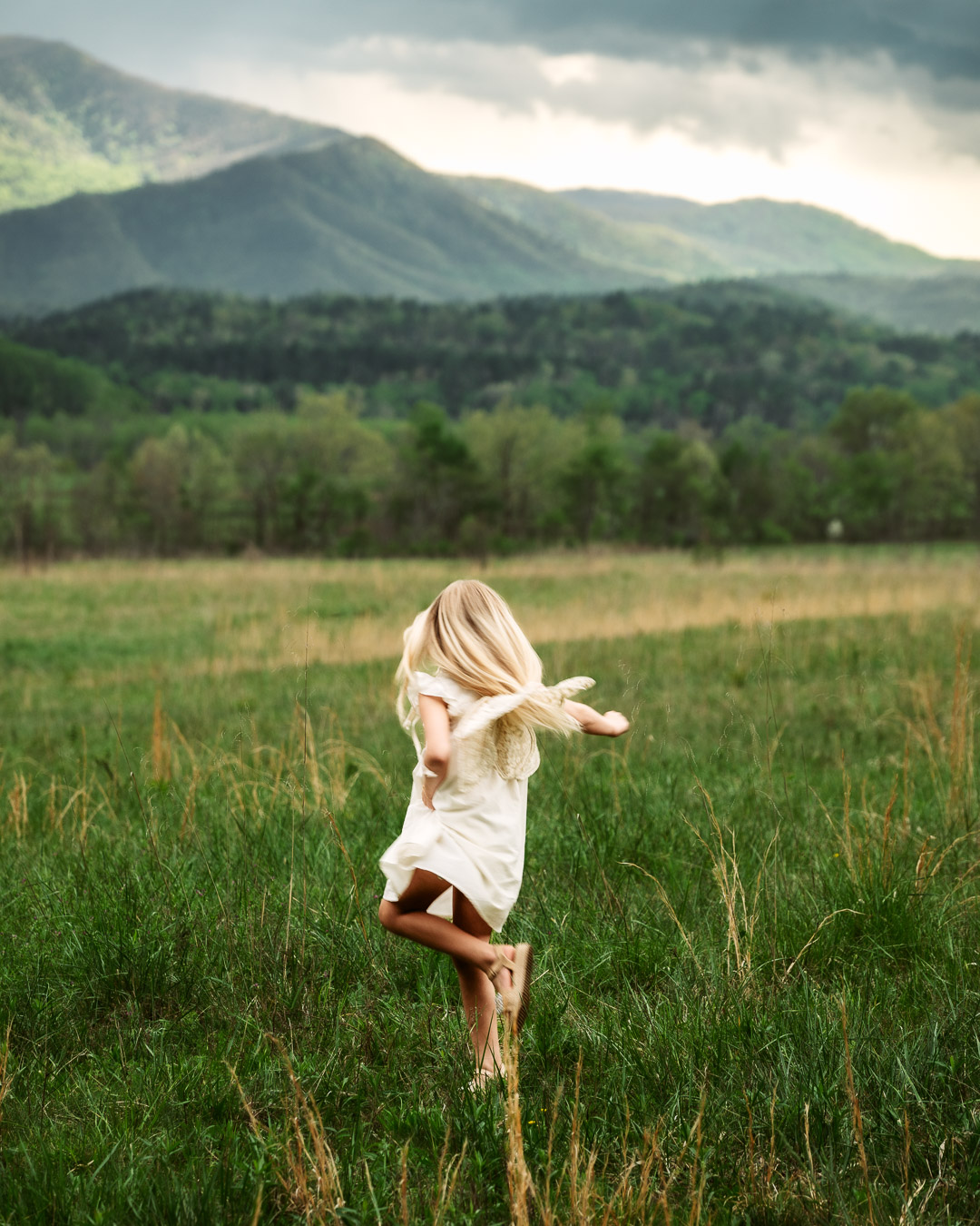 Fine art children's portrait of girl with fairy wings dancing in a sunlit field, by Tammy Jaquith Photography