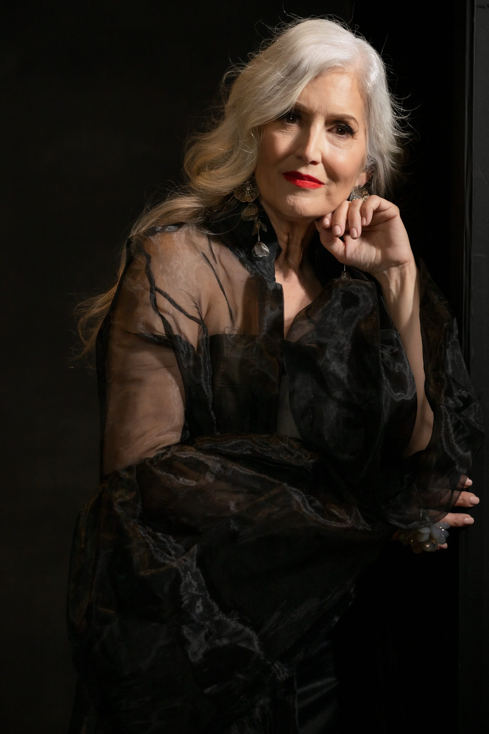 Elegant portrait of woman with silver hair and red lip in black sheer blouse, dramatic studio lighting by Tammy Jaquith Photography in Oregon